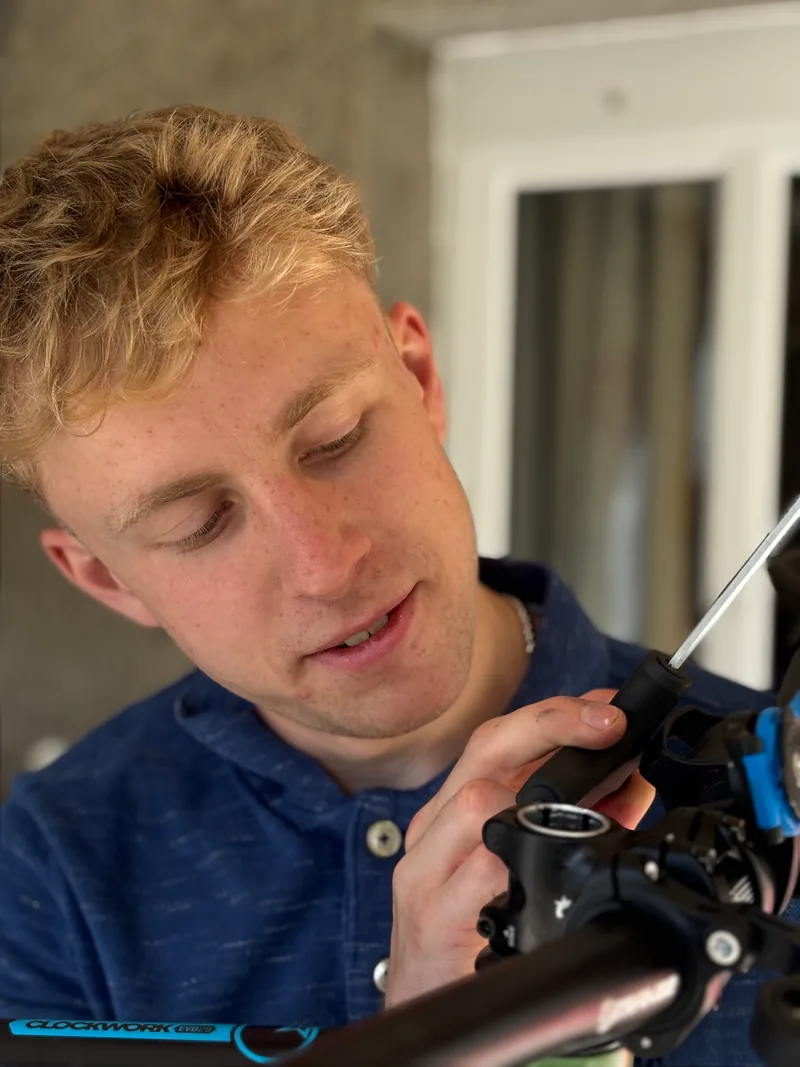 Callum examining a bicycle component by hand.