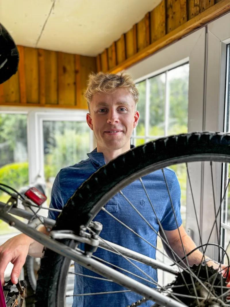 Callum behind a mountain bike on the workshop stand.